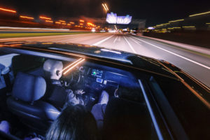driving at night on a highway with people in the car, seen through the glass roof